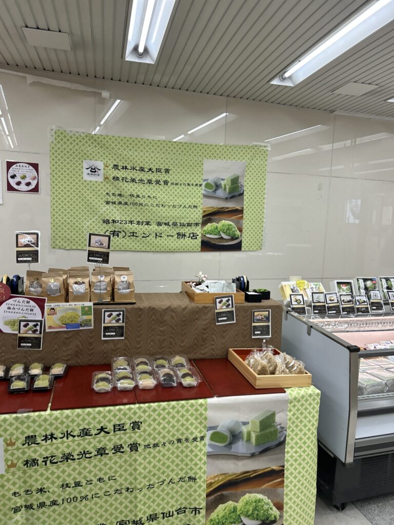 大丸の催事場に出店している仙台の老舗和菓子店「エンドー餅店」の看板と店舗外観。緑色の暖簾が目印。