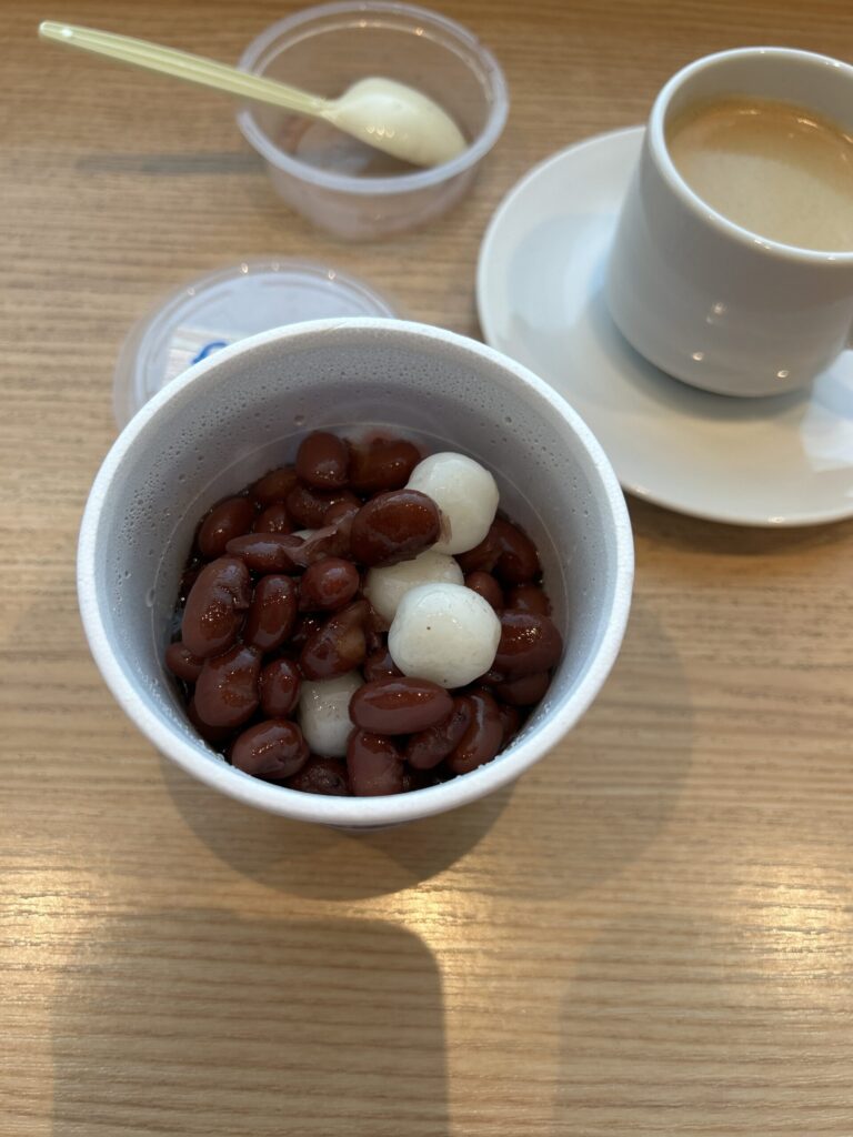 那覇空港の富士家（ふじや）沖縄ぜんざい。透明なカップに入った茶色の煮汁凍結氷と大粒の金時豆、白い白玉のクローズアップ写真。
