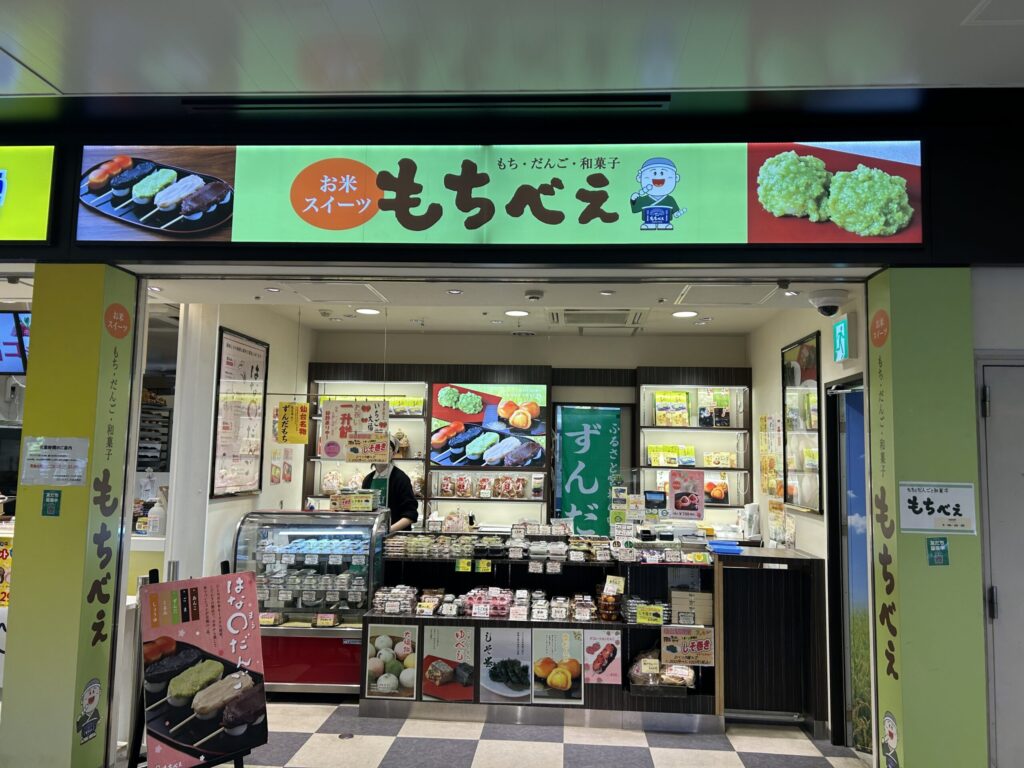 仙台駅エキナカ2階にある「もちべえ」の店舗外観。緑の暖簾とショーケースに並ぶお餅や団子。